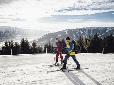 Two skiers enjoy a sunny descent in the mountains. | © Zell am See-Kaprun Tourismus