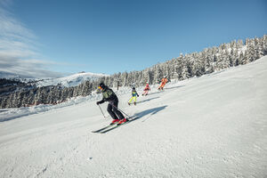 Eine Gruppe von Skifahrern genießt die Abfahrt im Schnee. | © Korbinian Seifert