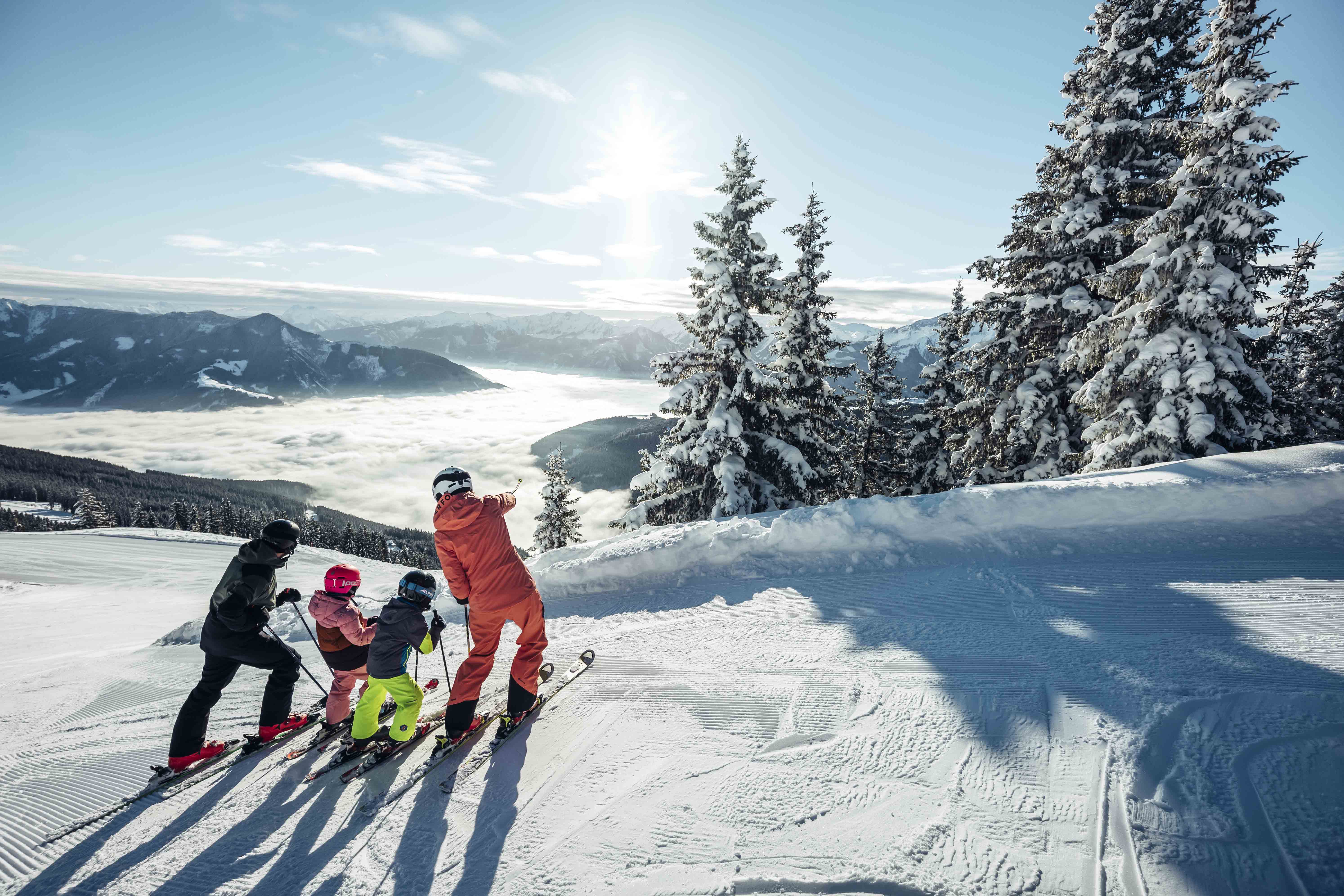 Eine Familie aus vier Personen steht beim Skifahren vor einer Winterlandschaft. | © Schmittenhöhebahn AG