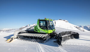 Eine grüne Pistenraupe steht auf einer schneebedeckten Piste. | © Schmittenhöhebahn AG/Nikolaus Faistauer Photography