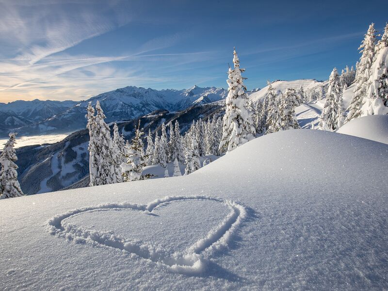 Winterlandschaft mit Herz im Schnee | © Schmittenhöhebahn AG/Nikolaus Faistauer Photography Verschneite Berge mit einem Herz im Schnee im Vordergrund. | © Schmittenhöhebahn AG/Nikolaus Faistauer Photography