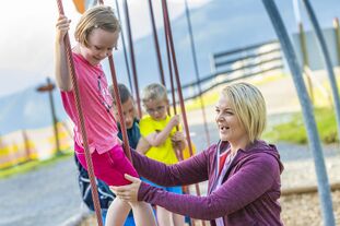 Eine Gruppe Kinder, die auf einem Spielplatz spielen und lachen. | © Schmittenhöhebahn AG/Max Steinbauer