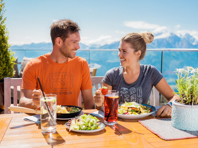 Paar genießt ein Essen im Bergrestaurant Franzl mit Blick auf die Berge. | © mr-offenblende.at