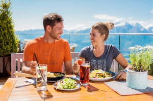 Paar genießt ein Essen im Bergrestaurant Franzl mit Blick auf die Berge. | © mr-offenblende.at