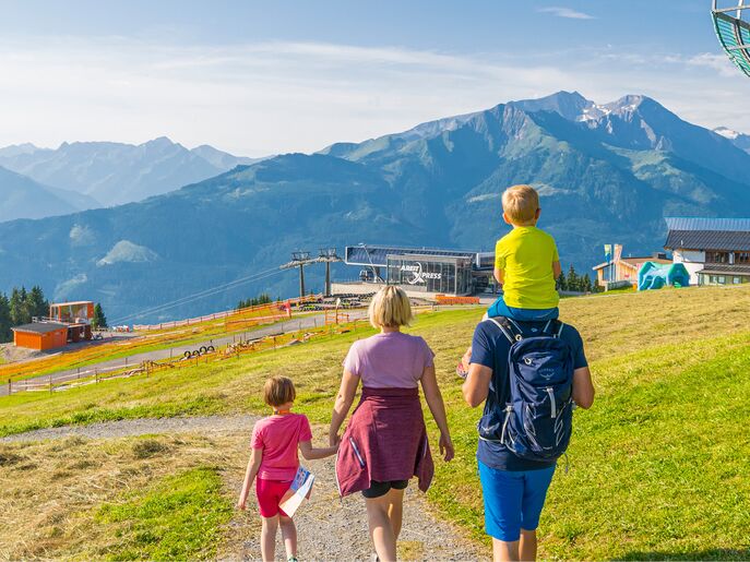 Eine Familie wandert durch grüne Wiesen mit Bergblick.