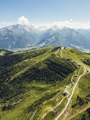 Eine Panoramaansicht der Alpen mit grünen Hügeln und einem blauen Himmel. | © Schmittenhöhebahn AG