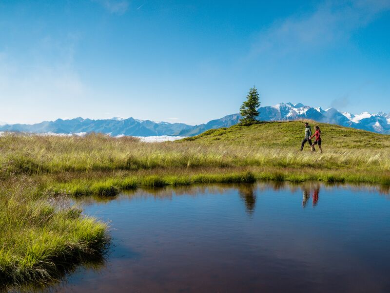 Hikers walking alongside the mountain lake Hikers walking alongside the mountain lake