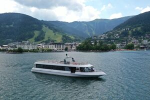 A modern boat on Lake Zell with mountains and a town in the background. | © Schmittenhöhebahn AG