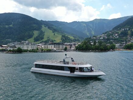 Ein modernes Boot auf dem Zeller See mit Bergen und Stadt im Hintergrund. | © Schmittenhöhebahn AG