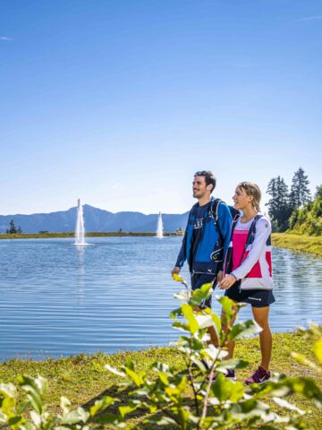 Zwei Personen stehen am See und genießen die Aussicht beim 4 Lakes Art Hike. | © Schmittenhöhebahn AG/Max Steinbauer