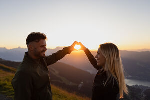 Foto von einem Pärchen, das vor dem Sonnenaufgang ein Herz mit ihren Händen formt. | © Kuscheiart