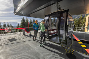 Two hikers enter a gondola at a mountain station. | © FotoAtelier Faistauer