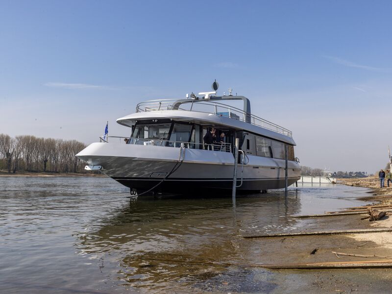 A modern ship docked at a riverbank under a blue sky. | © Schmittenhöhebahn AG