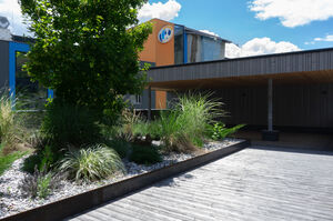 Modern building with garden and wooden veranda in sunshine. | © Schmittenhöhebahn AG